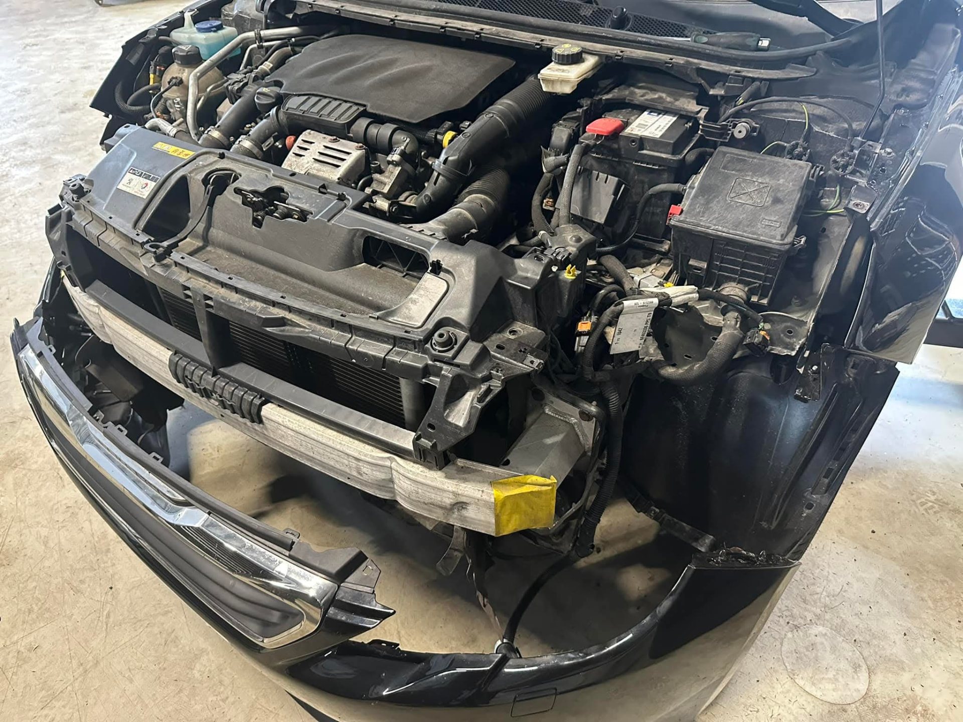 Bil med demonterad front under reparation